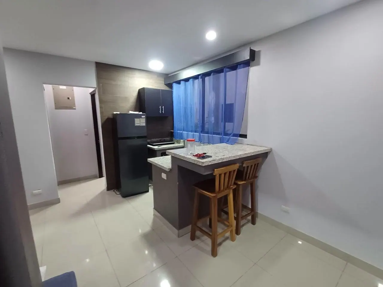 Cocina con refrigeradora y bancos de madera