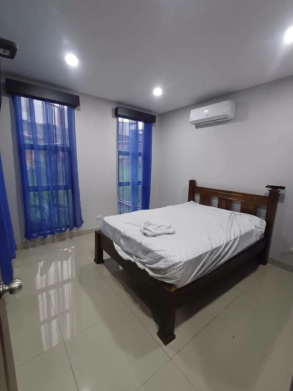 Habitación con cama, aire acondicionado y cortinas azules