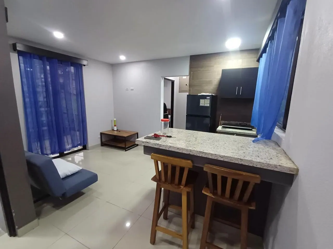 Sala con sofá cama y cocina con desayunador de granito