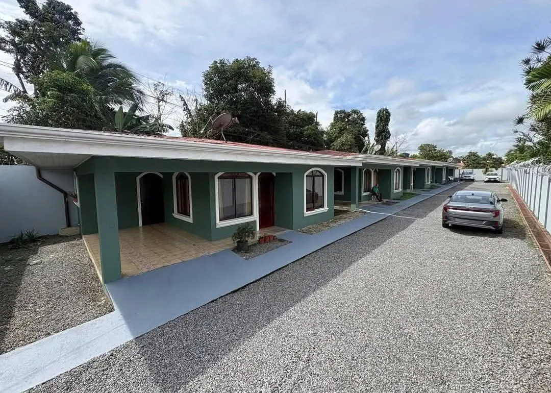 Hilera de apartamentos verdes con corredores y parqueo de lastre