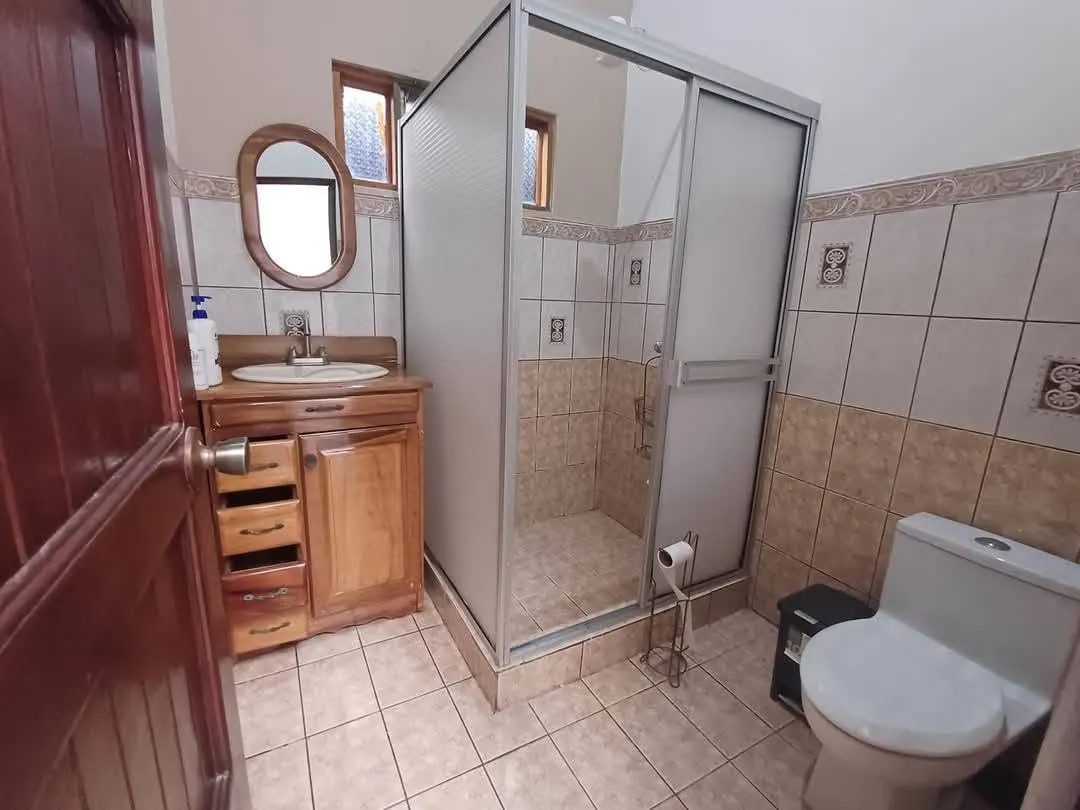 Baño con cancel de vidrio y mueble de madera