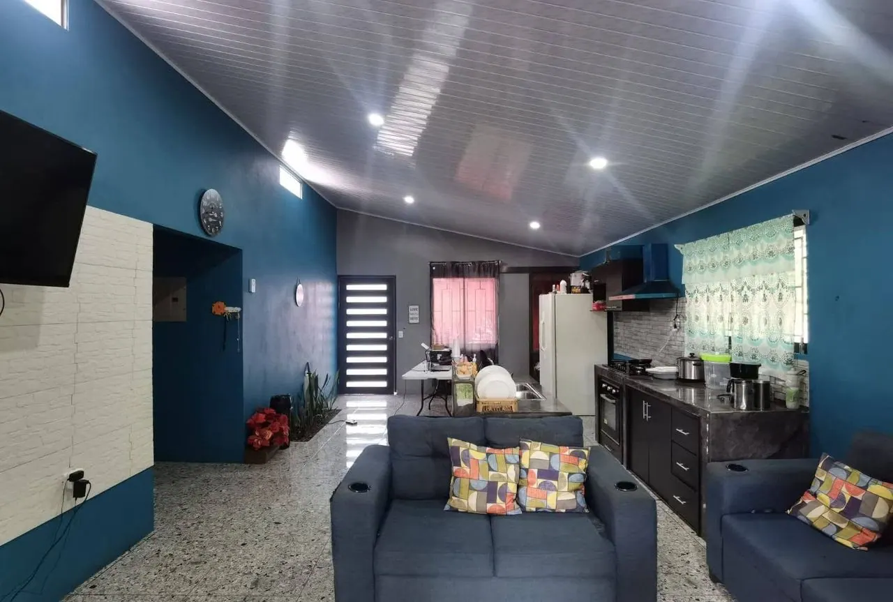 Sala con sillón gris y cocina integrada al fondo