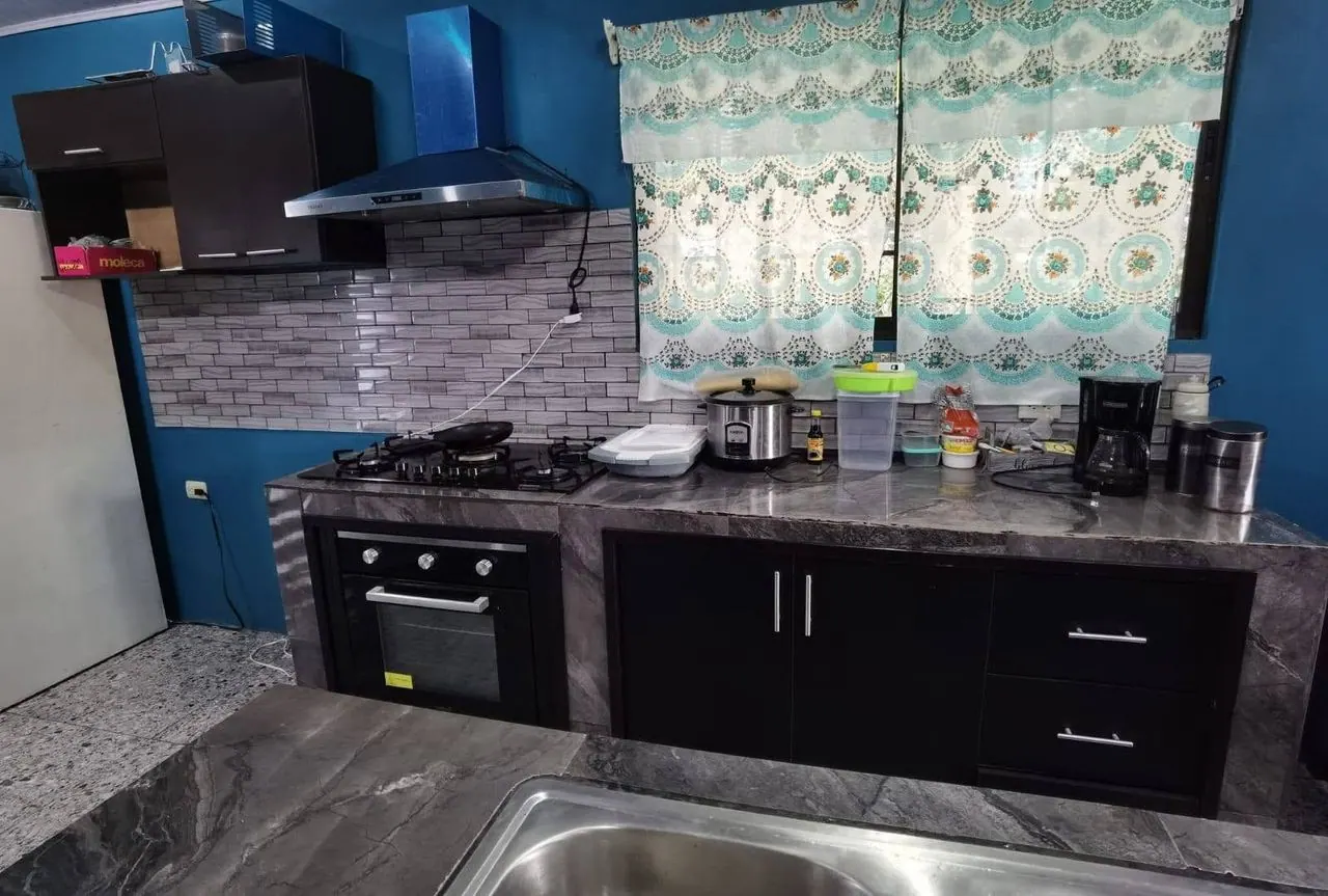 Cocina con muebles negros, horno empotrado y enchape de piedra