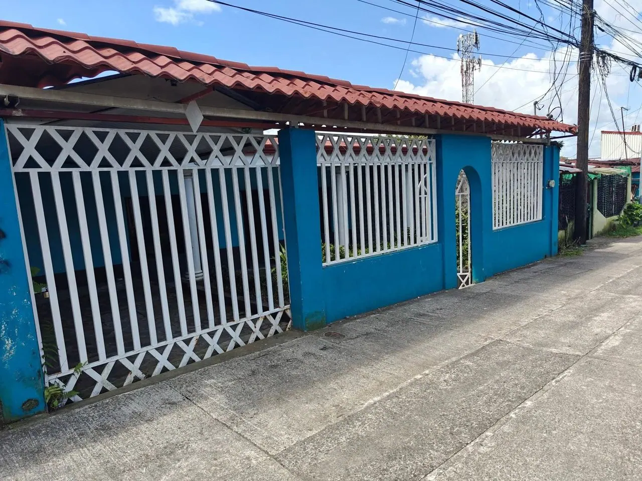 Fachada con verjas blancas y techo de teja