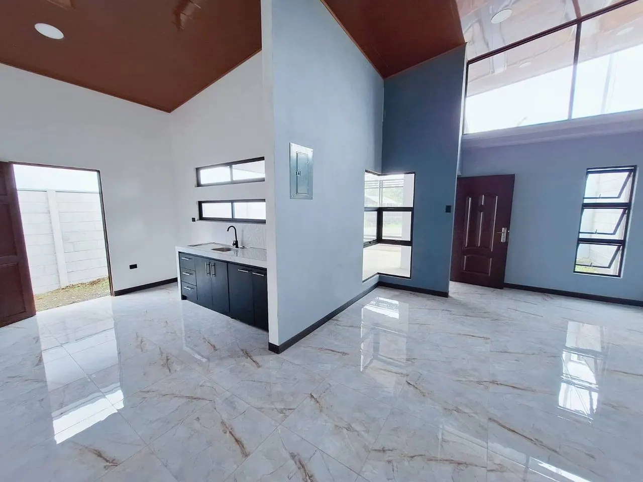 Cocina con muebles negros y ventanas altas