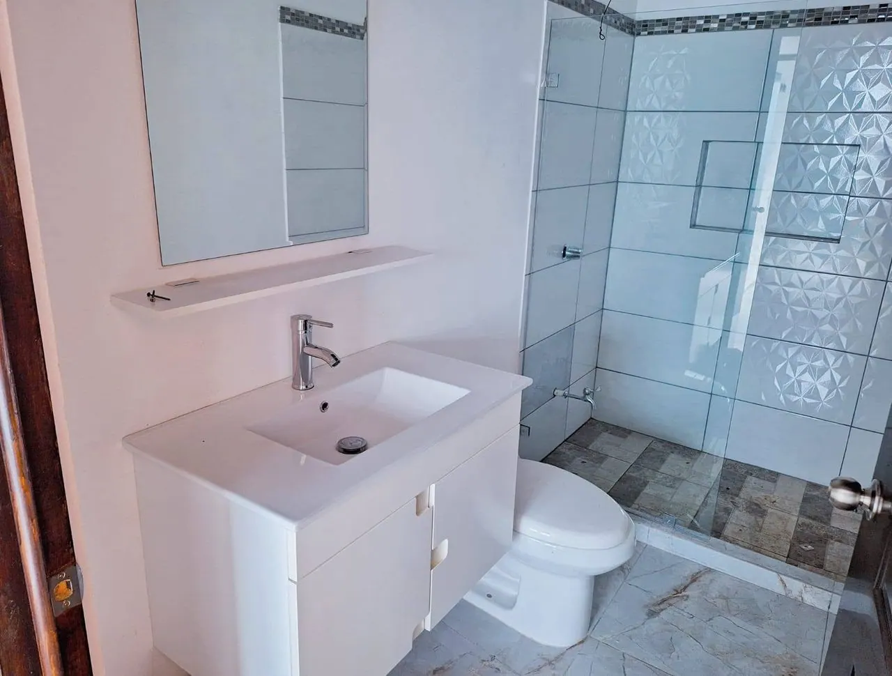 Baño con mueble blanco y ducha de vidrio
