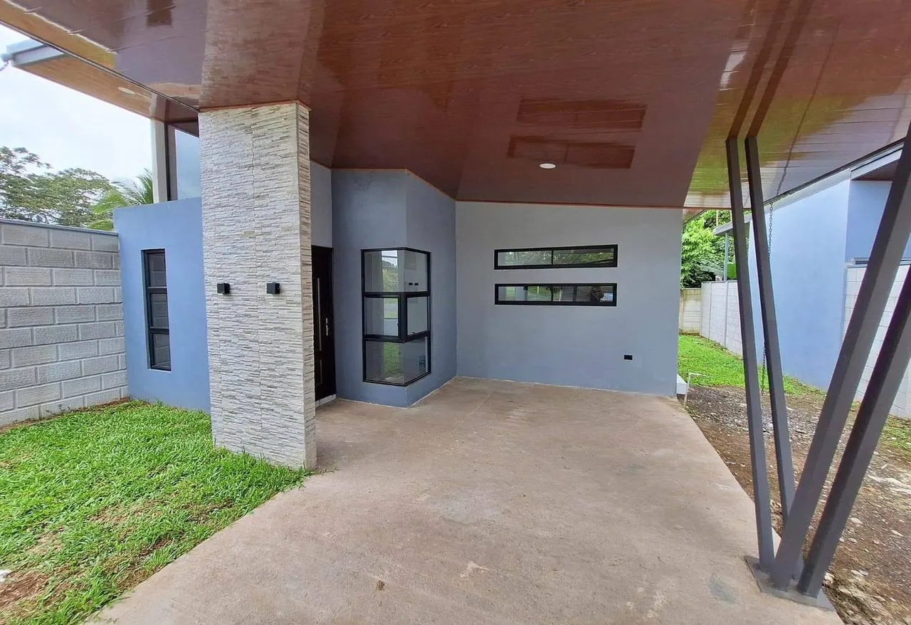 Casa nueva gris con columna de piedra y cochera techada