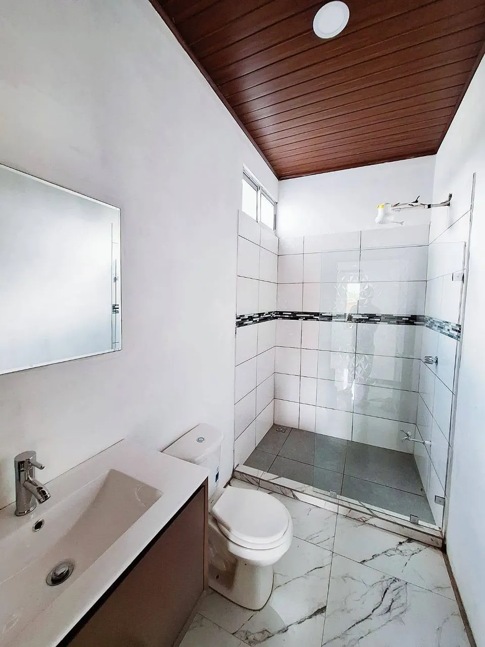 Baño con ducha de vidrio y enchape
