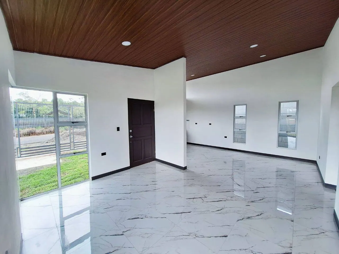 Sala amplia con piso tipo mármol y puerta al patio