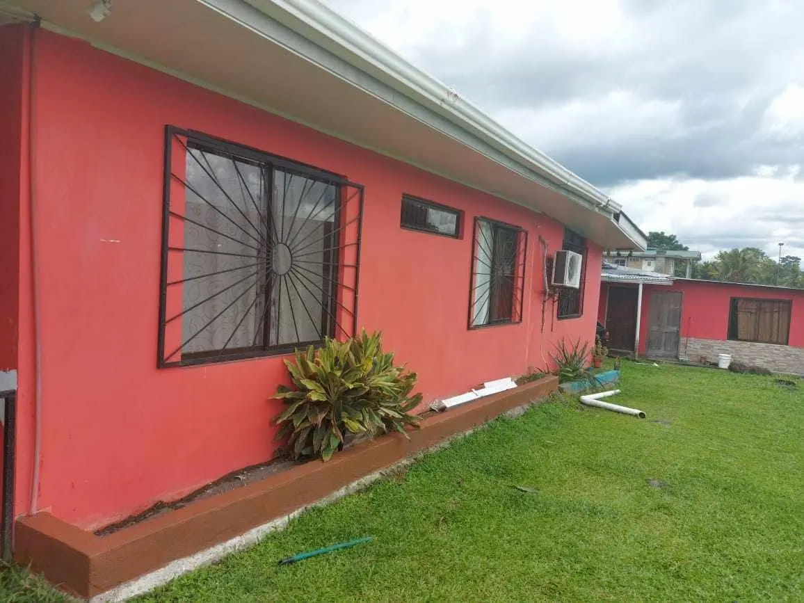 Casa roja con verjas y jardín de zacate