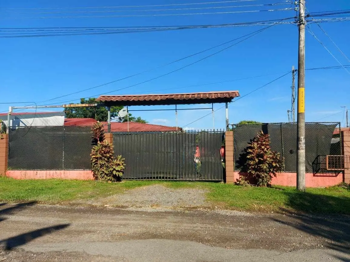 Portón y espacio de parqueo con rancho al fondo