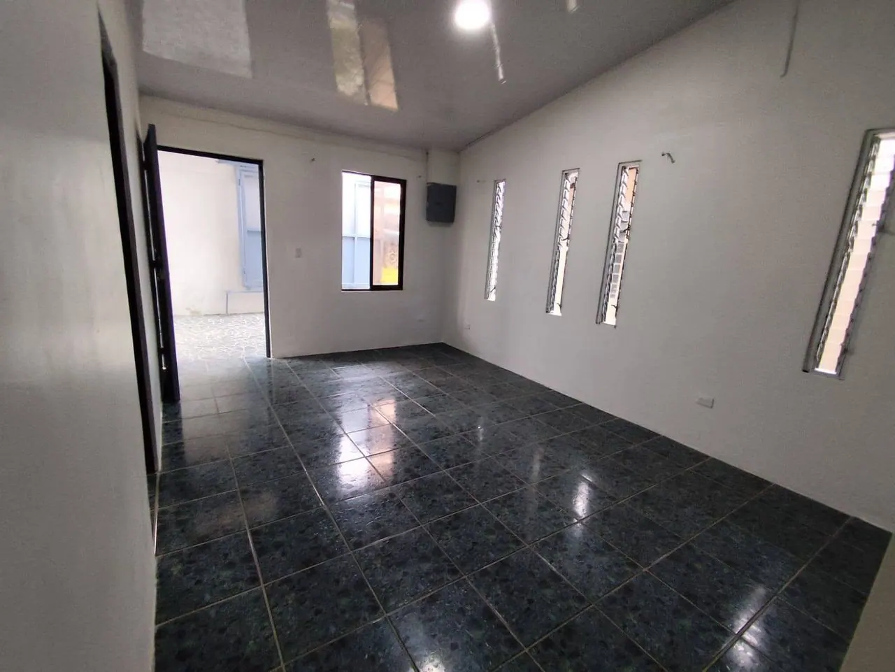 Sala con piso oscuro y ventanas angostas