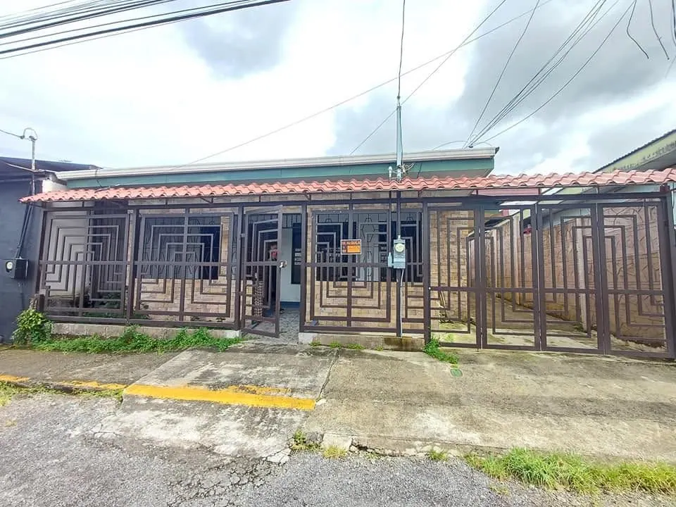 Casa con verjas café y techo de teja en Guápiles centro