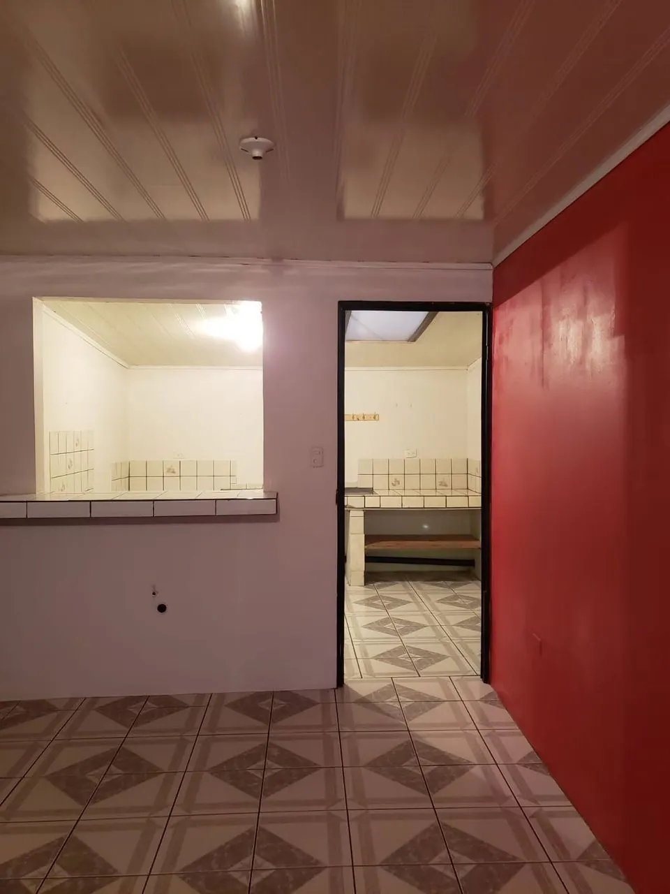 Cocina del apartamento vista desde la sala, con pared roja