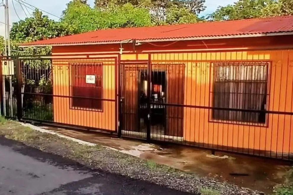 Casa de madera pintada de naranja con verja negra al frente