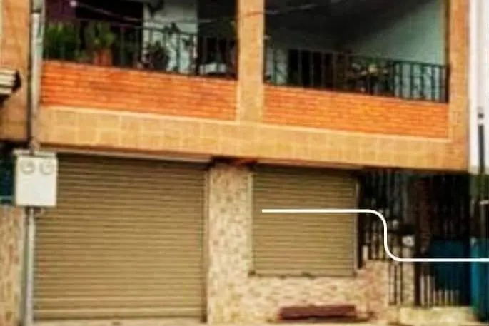 Edificio de dos plantas de ladrillo con balcón arriba y dos cortinas metálicas abajo