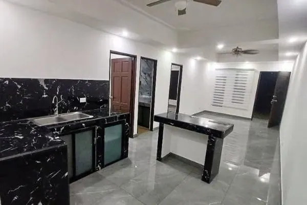 Cocina con mármol negro, desayunador y sala con abanico de techo