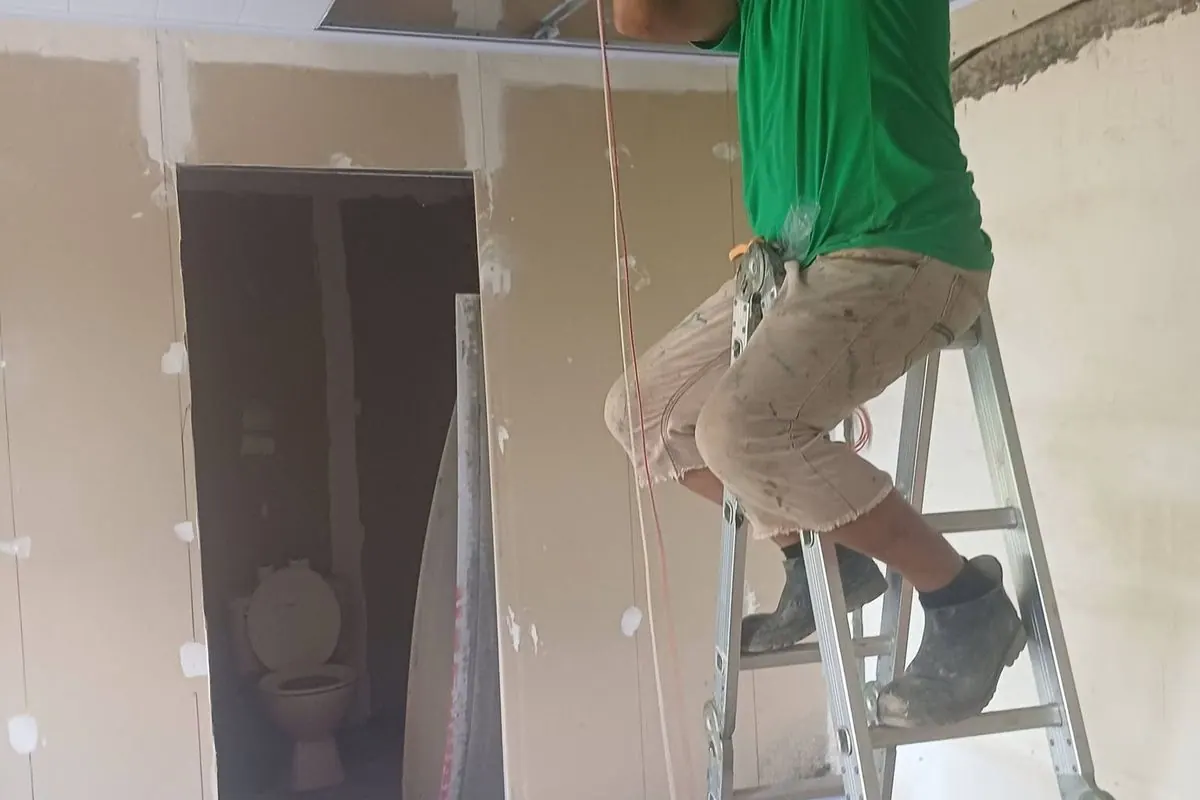 Trabajador instalando el cielo raso desde una escalera
